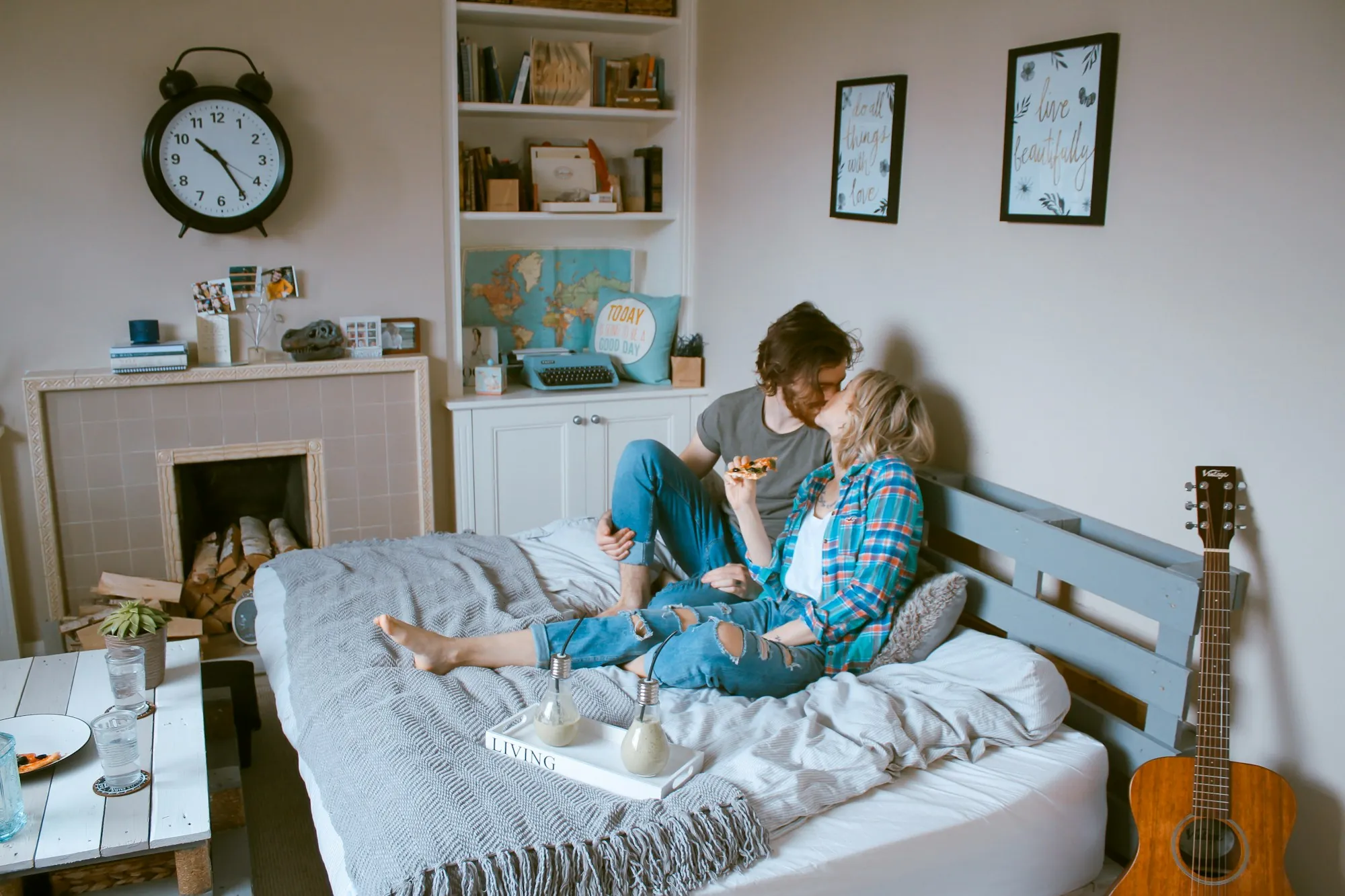 Couple sitting on a bed in a cozy room with a guitar nearby